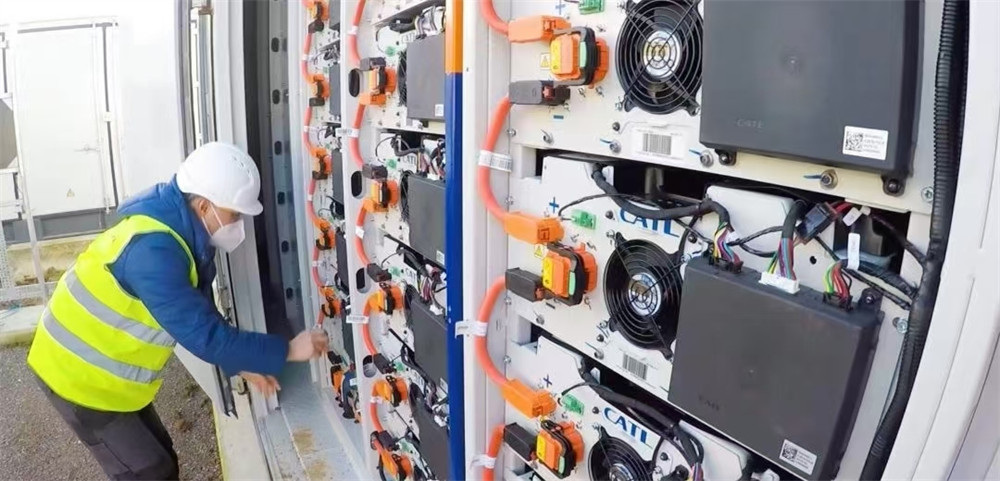 A technician inspecting a large-scale energy storage unit outdoors